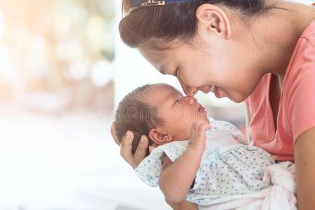 幸福的亚洲人母亲热烈地拥抱和接吻的她新生的婴儿