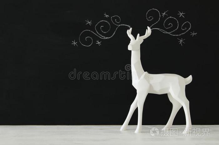 白色的驯鹿向木制的表越过黑板背景惠斯