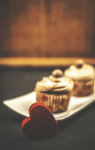 巧克力纸杯蛋糕和红色的木制的心向木制的和黑的背