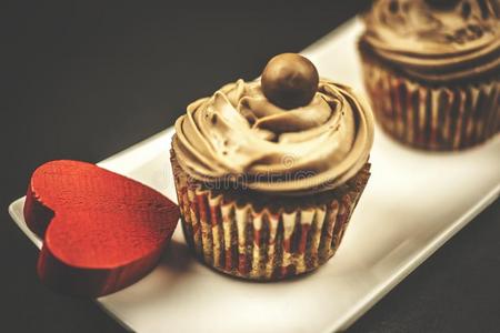 巧克力纸杯蛋糕和红色的木制的心向木制的和黑的背