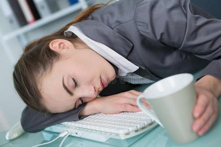 美丽的疲倦的女人睡眠向键盘便携式电脑照片