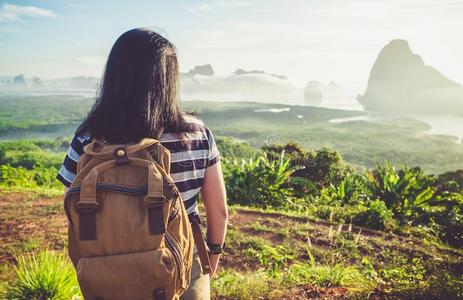 幸福的年幼的旅行支票女人背着背包徒步旅行的人有样子的向后的向照相机