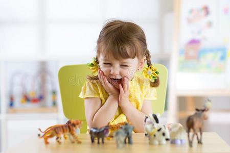 幸福的小的小孩演奏动物玩具在家或日托中心