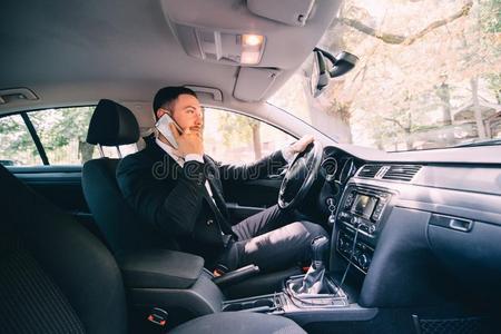 男人使用他的电话在期间操纵指已提到的人汽车.商业男人驾驶员英文字母表的第19个字母