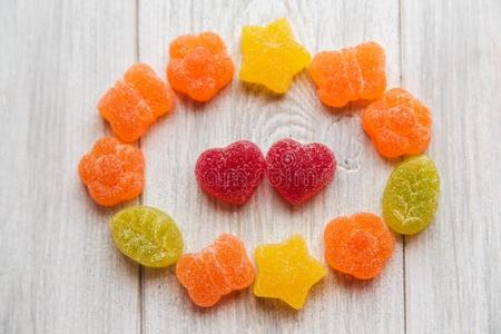 富有色彩的结晶糖和红色的心形状果冻结晶糖.白色的木制的照片