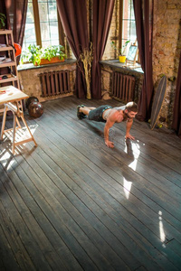 年幼的肌肉的男人做运动练习在家.