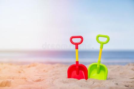 绿色的和红色的塑料制品铲子向指已提到的人海滩