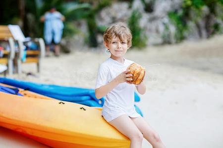 小的小孩男孩喝饮料椰子果汁向热带的海滩