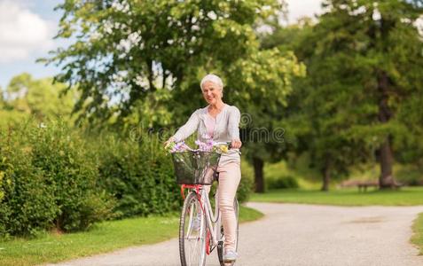 幸福的较高的女人骑马自行车在夏公园