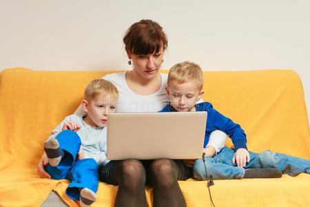 两个小的男孩和母亲使用便携式电脑