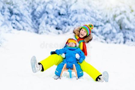 母亲和婴儿向雪橇乘.冬雪乐趣.