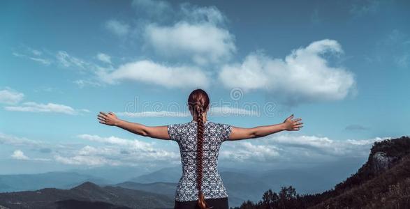 年幼的女人远足者和敞开的武器在山山峰,自由自负