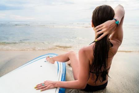 女性的冲浪运动员一次紧接在后的向板后的冲浪运动在海滩