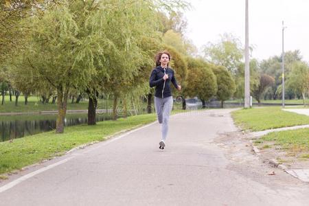 年幼的幸福的女人慢跑采用秋公园.Runn采用g健康女孩