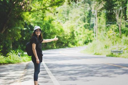 搭便车的旅行者女人和帽子和背包步行向一ro一d