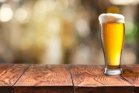 玻璃关于啤酒向木制的表和变模糊背景.
