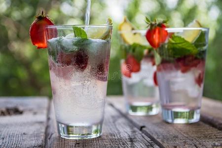草莓的橙片新鲜的柠檬汽水和稻草人,薄荷和冰照片