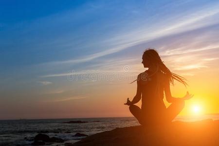 瑜伽女人轮廓向指已提到的人洋在的时候日落.