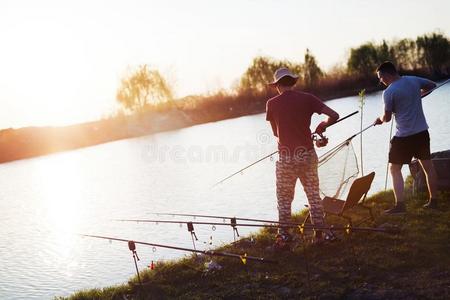 年幼的男人捕鱼向湖在日落享有业余爱好