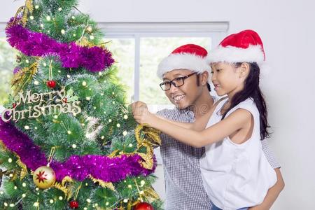 小的女孩装饰圣诞节树和她fat她