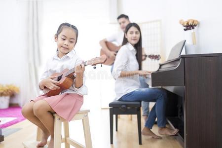 亚洲人家庭,女儿演奏夏威夷的四弦琴,父亲演奏吉他,飞蛾