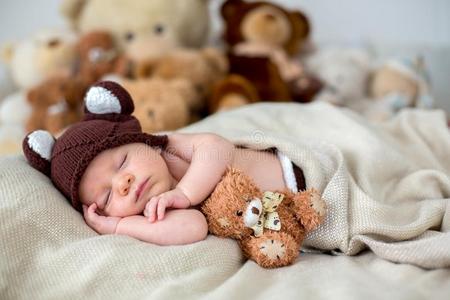小的新生的婴儿男孩,睡眠和妇女连衫衬裤熊在家采用床