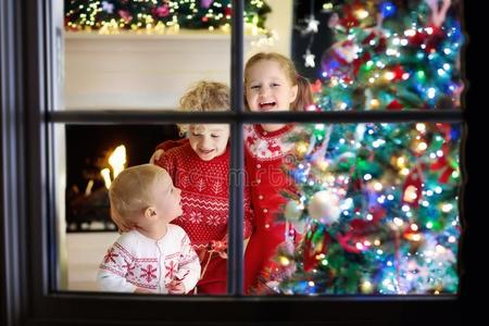 孩子们在圣诞节树.小孩在壁炉向圣诞节前夕