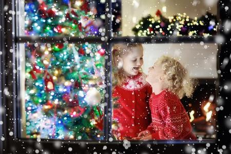 孩子们在圣诞节树.小孩在壁炉向圣诞节前夕
