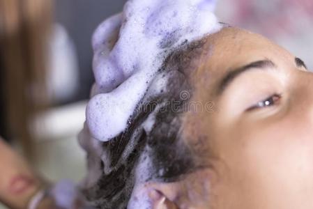 年幼的女人洗涤头发采用沙龙