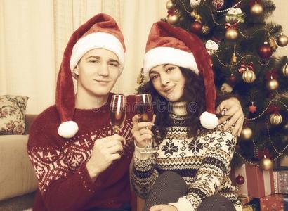 幸福的对坐在近处圣诞节树和玻璃关于香槟酒.winter冬天
