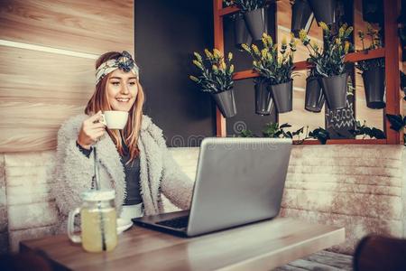 美丽的年幼的女人使用便携式电脑采用咖啡馆