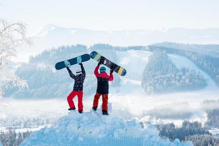 两个人台向雪堆和提升他们的滑雪板在上面