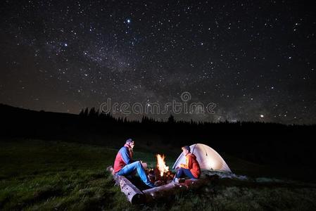 旅行者在近处营火和帐篷在下面夜布满星星的天