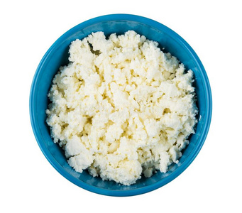 粒状的小屋奶酪采用蓝色碗隔离的向白色的
