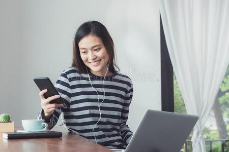 幸福的亚洲人女人使用闲谈和可移动的和使用便携式电脑比较两个或多个文件