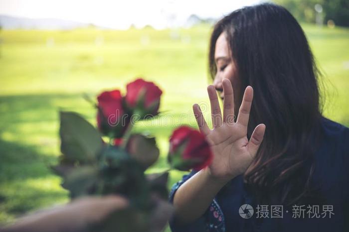 一亚洲人女人拒绝一红色的玫瑰花从她男朋友向