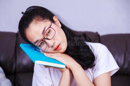 欲睡的女人和阅读无聊的书向沙发