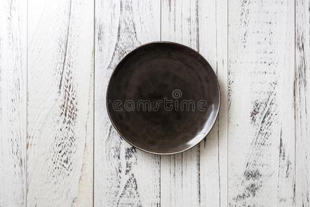 黑的盘子向白色的木制的背景