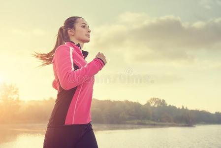 美丽的年幼的女人跑步在指已提到的人湖