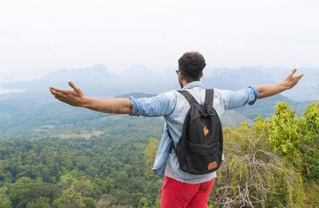 旅行者男人和背包起立向山顶凸起的手