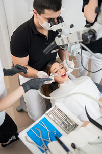 牙科医生和两个女性的助手处理有耐性的牙和demand需要