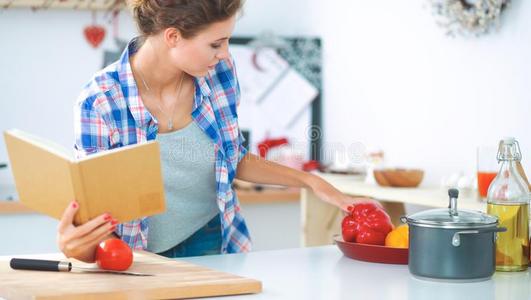 年幼的女人阅读食谱采用指已提到的人厨房,look采用g为食谱