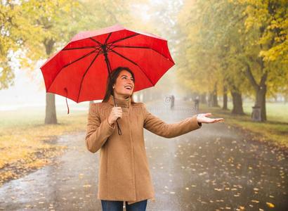 幸福的女人和红色的雨伞步行在指已提到的人雨采用美丽的一