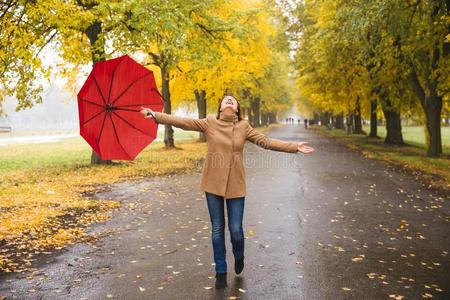 幸福的女人和红色的雨伞步行在指已提到的人雨采用美丽的一