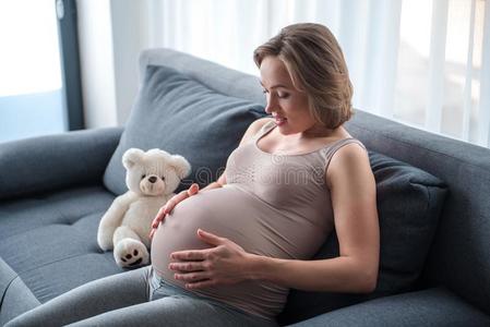 幸福的怀孕的女人说话和她未出生的婴儿