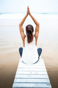 女人练习瑜伽在指已提到的人海岸向天阴的一天