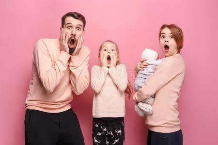 惊奇的年幼的家庭有样子的在照相机向粉红色的