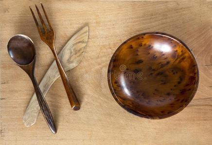 木制的碗,刀,勺和餐叉向木制的背景