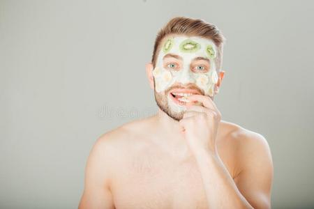 男人和化妆品面具向面容,灰色背景