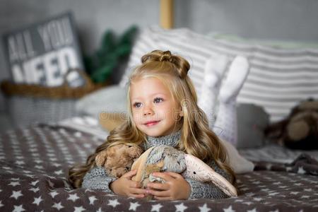 漂亮的小的女孩是be的三单形式演奏和一玩具be一r向指已提到的人床